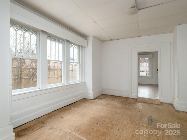 spare room with a paneled ceiling and baseboards