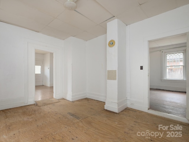 spare room featuring a paneled ceiling and baseboards