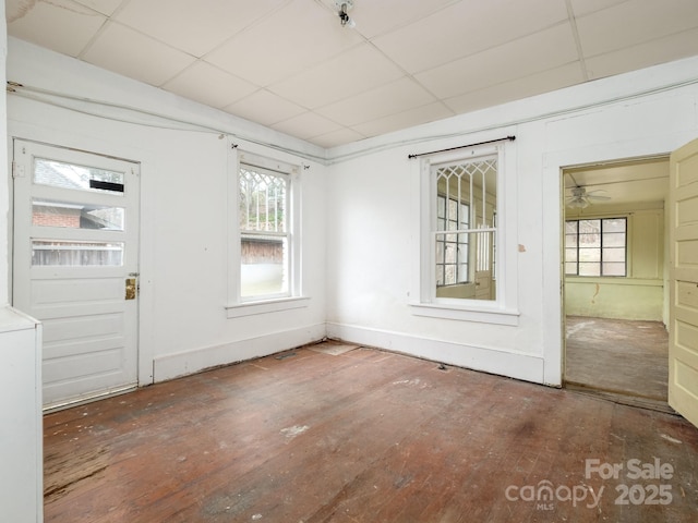 spare room featuring hardwood / wood-style flooring, a paneled ceiling, and baseboards