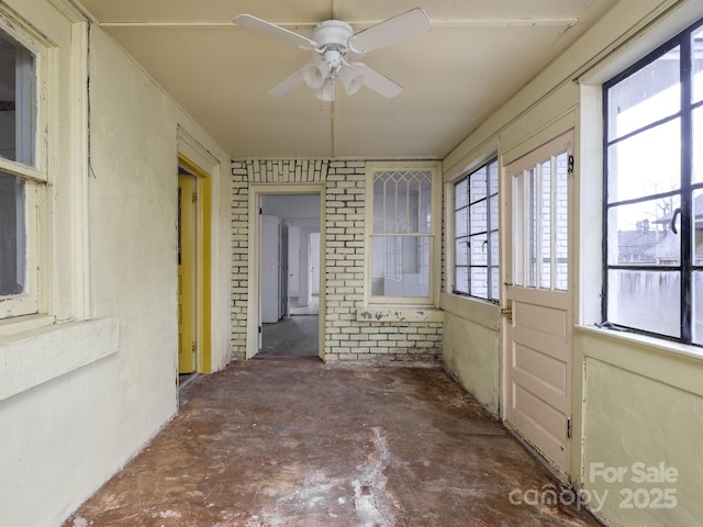 unfurnished sunroom with ceiling fan