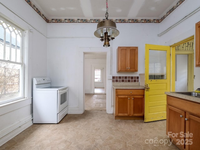 kitchen featuring light countertops, brown cabinetry, plenty of natural light, and white electric range oven