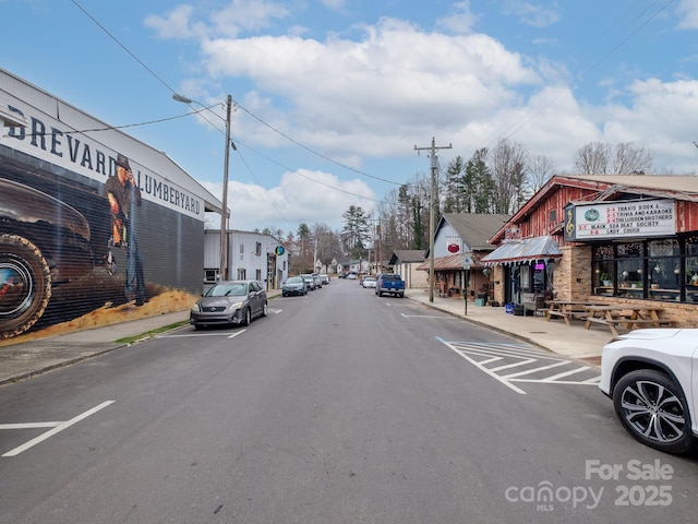 view of road with sidewalks, street lights, and curbs