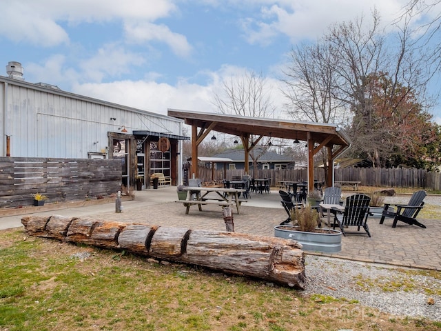 view of property's community with a gazebo, an outdoor fire pit, a patio area, and fence