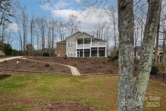 back of property featuring a balcony, a sunroom, and a yard