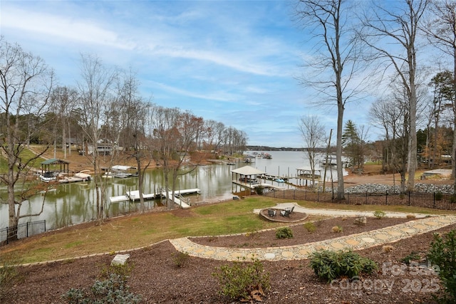 view of yard with a dock, a water view, and fence