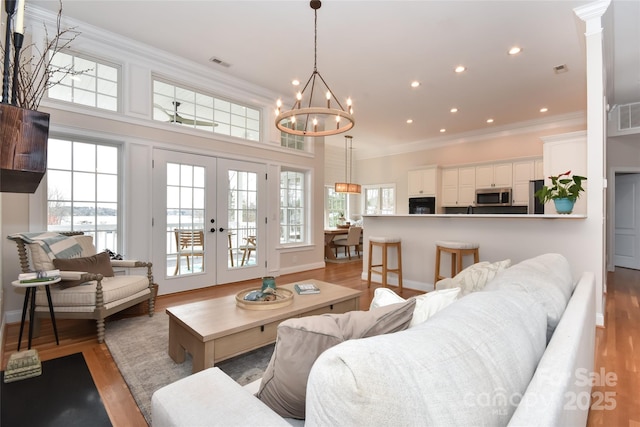 living area featuring plenty of natural light, crown molding, visible vents, and wood finished floors