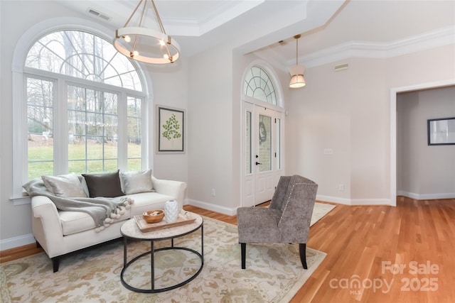 living room featuring baseboards, wood finished floors, visible vents, and a notable chandelier