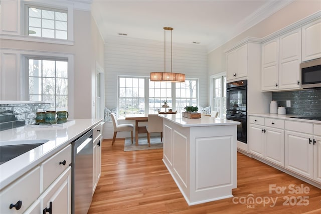 kitchen with black appliances, light wood finished floors, backsplash, and light countertops