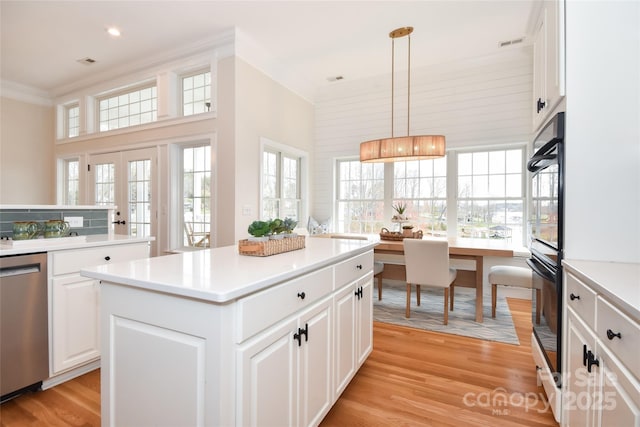 kitchen featuring a center island, french doors, stainless steel dishwasher, ornamental molding, and light wood-type flooring