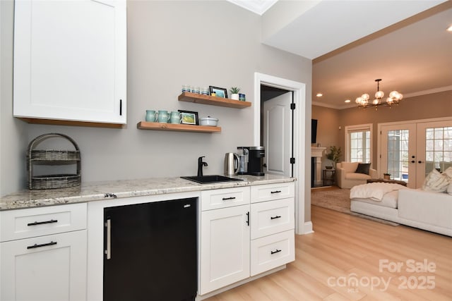 kitchen featuring crown molding, freestanding refrigerator, white cabinetry, and a sink