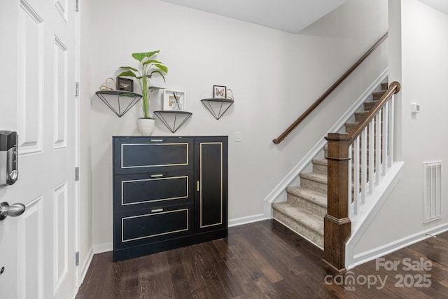 entrance foyer featuring dark wood-style flooring, visible vents, baseboards, and stairs