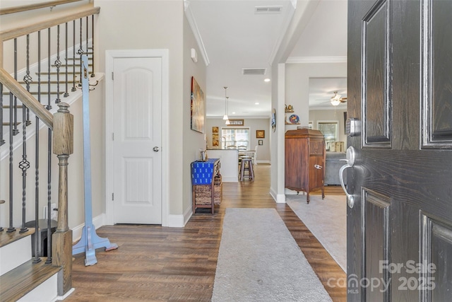 foyer with dark wood-style floors, stairs, visible vents, and ornamental molding