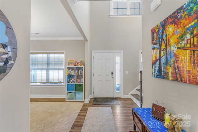 foyer featuring ornamental molding, dark wood-style flooring, a high ceiling, and baseboards