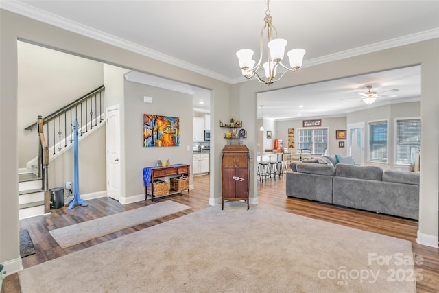 carpeted living area with stairs, ornamental molding, wood finished floors, and baseboards