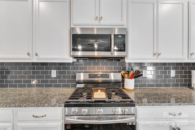 kitchen featuring appliances with stainless steel finishes, stone counters, white cabinetry, and backsplash