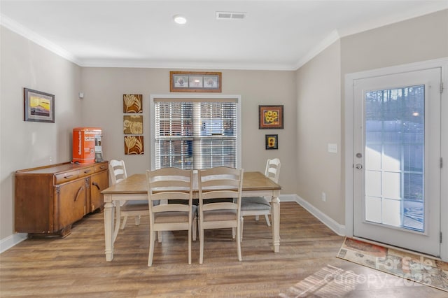 dining area featuring baseboards, light wood finished floors, and crown molding