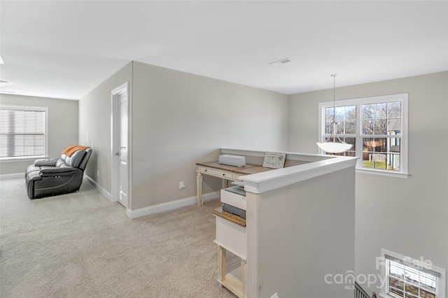 corridor with light carpet, baseboards, an upstairs landing, and a healthy amount of sunlight