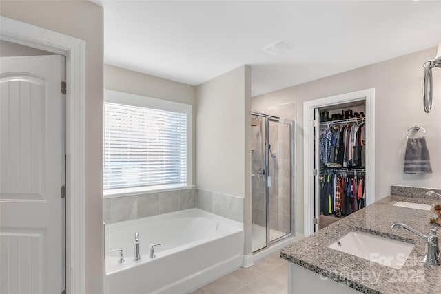 bathroom featuring a sink, a spacious closet, a shower stall, and double vanity