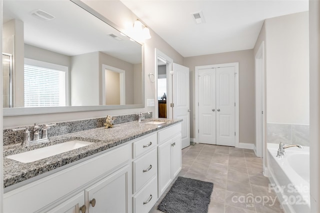 full bathroom featuring a garden tub, double vanity, a closet, visible vents, and a sink