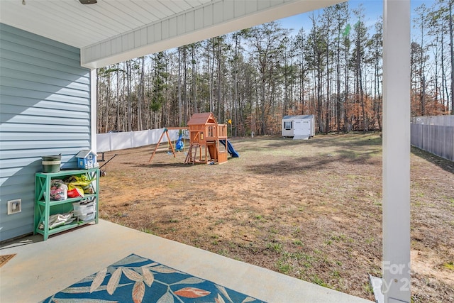 view of yard featuring a storage shed, a patio, a fenced backyard, an outbuilding, and a playground