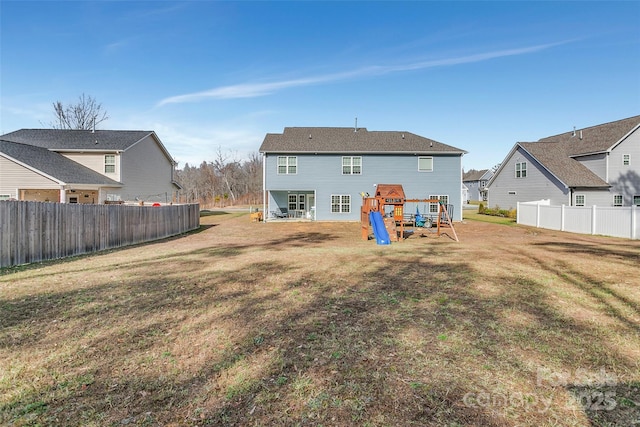 rear view of property with a lawn, a residential view, fence, and a playground