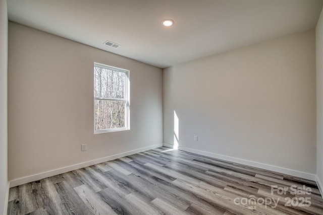 empty room featuring visible vents, light wood-style flooring, and baseboards