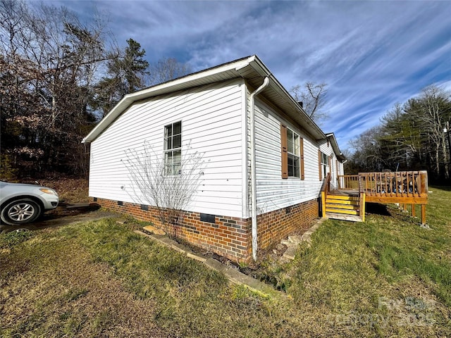 view of side of home featuring a deck, crawl space, and a lawn