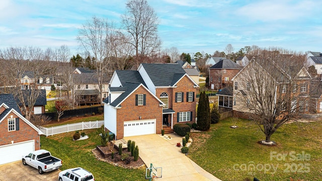 traditional home featuring a garage, fence, concrete driveway, a residential view, and a front lawn