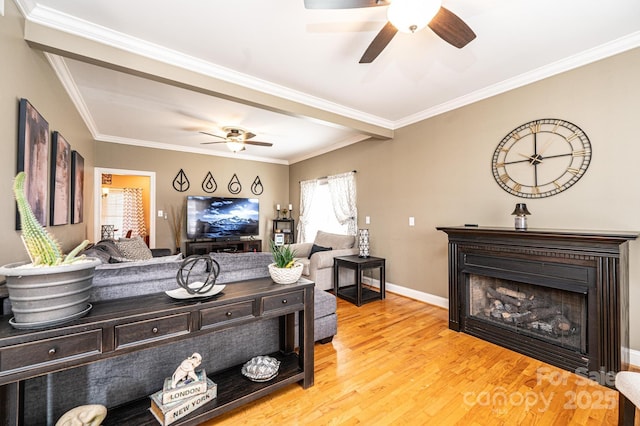 living area featuring a fireplace, ornamental molding, ceiling fan, wood finished floors, and baseboards