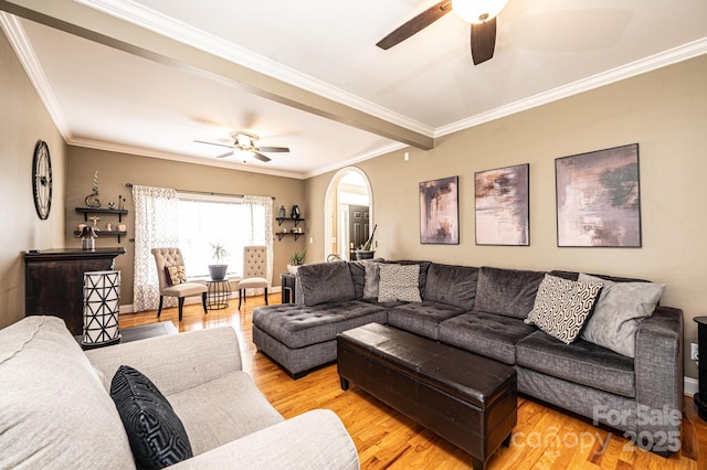 living room featuring light wood-type flooring, ceiling fan, arched walkways, and crown molding