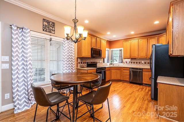 kitchen featuring a sink, light countertops, ornamental molding, appliances with stainless steel finishes, and pendant lighting