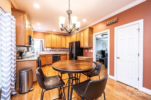 kitchen featuring decorative backsplash, light wood-style flooring, light countertops, crown molding, and black appliances