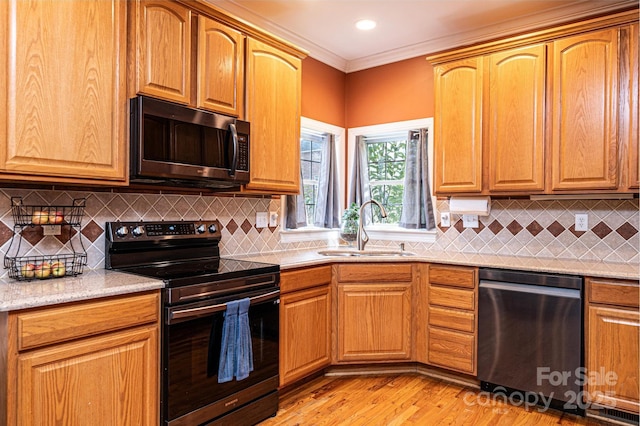 kitchen featuring light wood finished floors, decorative backsplash, appliances with stainless steel finishes, ornamental molding, and a sink