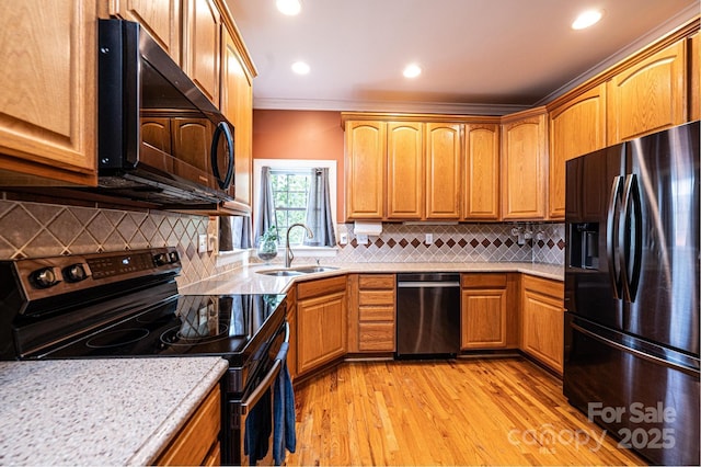 kitchen featuring light wood finished floors, decorative backsplash, ornamental molding, a sink, and black appliances