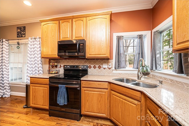 kitchen featuring light stone counters, stainless steel microwave, black range with electric stovetop, ornamental molding, and a sink