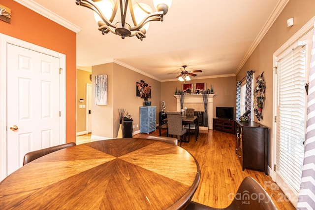 dining room featuring ornamental molding, ceiling fan with notable chandelier, and wood finished floors