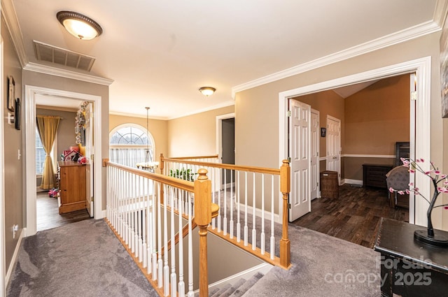 hallway featuring dark wood-style floors, visible vents, crown molding, and an upstairs landing