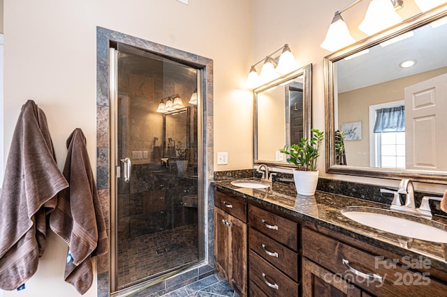 full bathroom with a sink, a shower stall, and double vanity