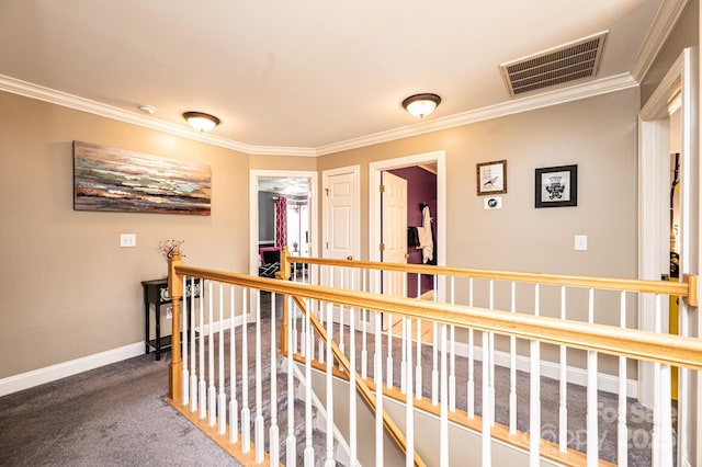 hall with carpet floors, crown molding, visible vents, an upstairs landing, and baseboards