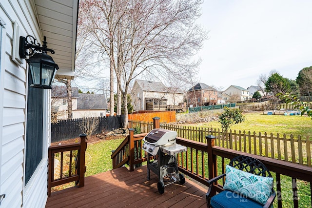 wooden deck with a lawn, a grill, a residential view, and a fenced backyard