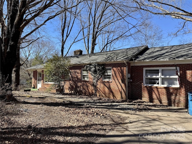 single story home with brick siding and a chimney