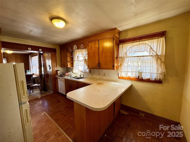 kitchen featuring white appliances, a peninsula, light countertops, open shelves, and a sink