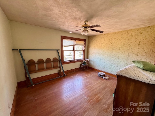 unfurnished bedroom with dark wood-style floors, ceiling fan, a textured ceiling, and baseboards