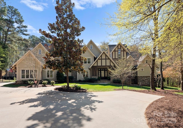 english style home with a front yard and stone siding