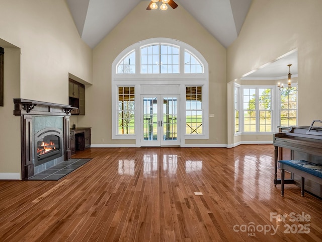 living area featuring high vaulted ceiling, a tiled fireplace, and wood finished floors