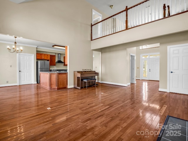 unfurnished living room featuring dark wood-style floors, a high ceiling, an inviting chandelier, and baseboards