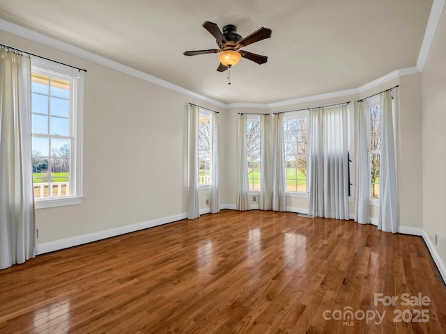 empty room with baseboards, hardwood / wood-style floors, a ceiling fan, and crown molding