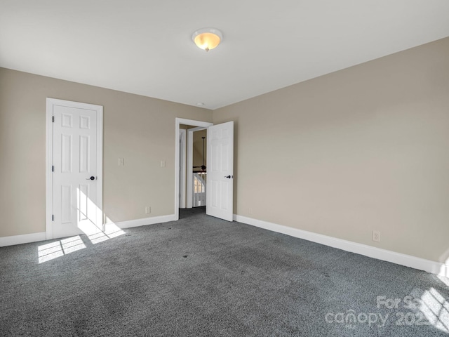 unfurnished bedroom featuring dark carpet and baseboards