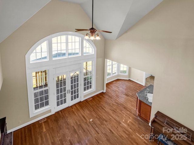 unfurnished living room with high vaulted ceiling, french doors, visible vents, and wood finished floors