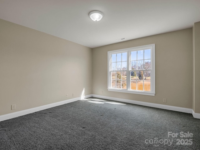 spare room featuring carpet floors, visible vents, and baseboards